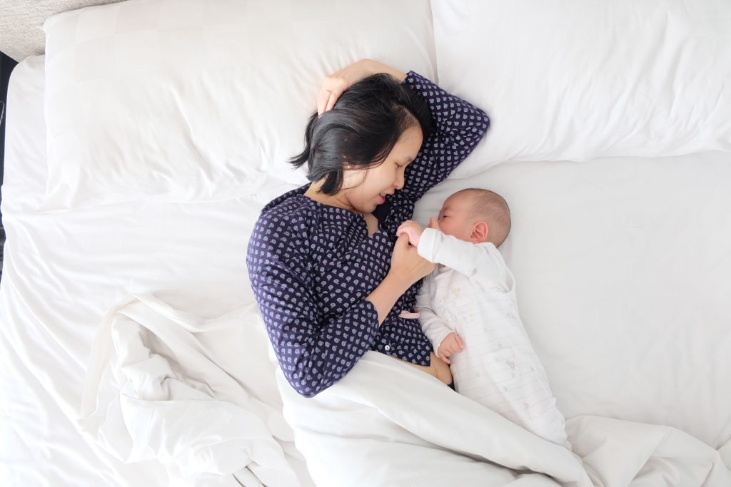 mom and baby laying on bed
