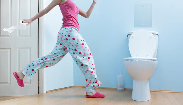 woman running to washroom with toilet paper in hand