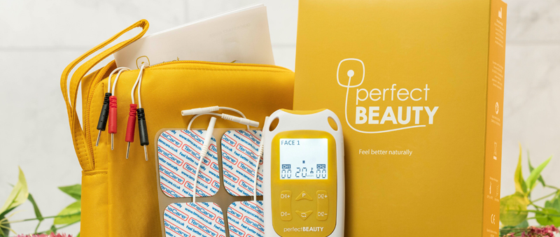 MCP_Blog_How_Tenscare_Perfect_Beauty Yellow cosmetic bag, electrode pads, and a digital device labelled "perfect BEAUTY" are displayed with a matching yellow box.